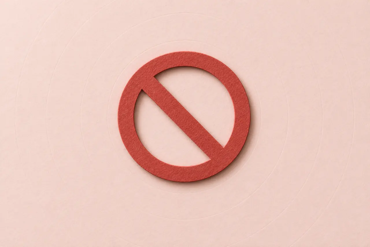 Un panneau d’interdiction en papier découpé rouge, sur un papier rose pâle.