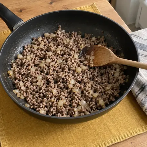 Étape 2 : Pendant ce temps, faites revenir l’oignon 5 minutes dans l’huile à feu moyen. Ajoutez la viande et émiettez-la à la cuillère en bois : laissez-la cuire 8 à 10 minutes, jusqu’à ce qu’il ne reste plus aucune trace rose.