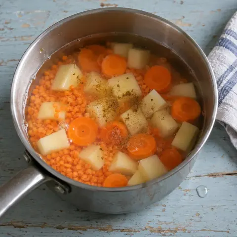 Étape 2 : Mettez-les dans une casserole avec les carottes, la pomme de terre, le cumin et l’eau.