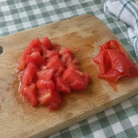 Étape 2 : Plongez la tomate 30 secondes dans l’eau bouillante, pelez-la, retirez les pépins et coupez-la en morceaux.