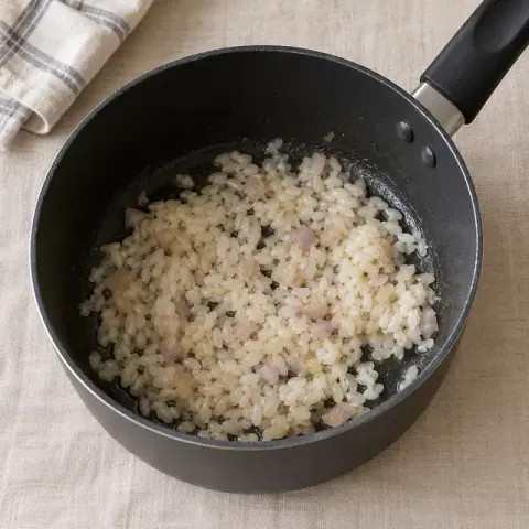 Étape 1 : Dans une casserole à fond épais, faites fondre l’échalote 2 minutes à feu doux dans 1 c. à café d’huile d’olive, sans la laisser colorer. Ajoutez le riz et remuez 1 minute, jusqu’à ce que les grains deviennent translucides.