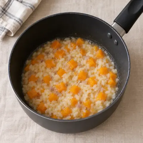 Étape 2 : Ajoutez le potimarron et le tiers de l’eau chaude. Laissez cuire à petit feu en remuant souvent, et versez le reste de l’eau peu à peu, à mesure que le riz l’absorbe.