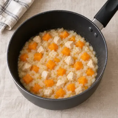 Étape 3 : Au bout de 10 minutes, ajoutez les dés de poulet et poursuivez 15 à 20 minutes : le riz doit être très tendre, le potimarron fondu, et le poulet blanc à cœur, sans trace rosée (coupez le plus gros dé pour vérifier).